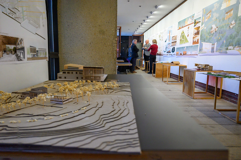 An architecture model in the foreground and people talking in the background