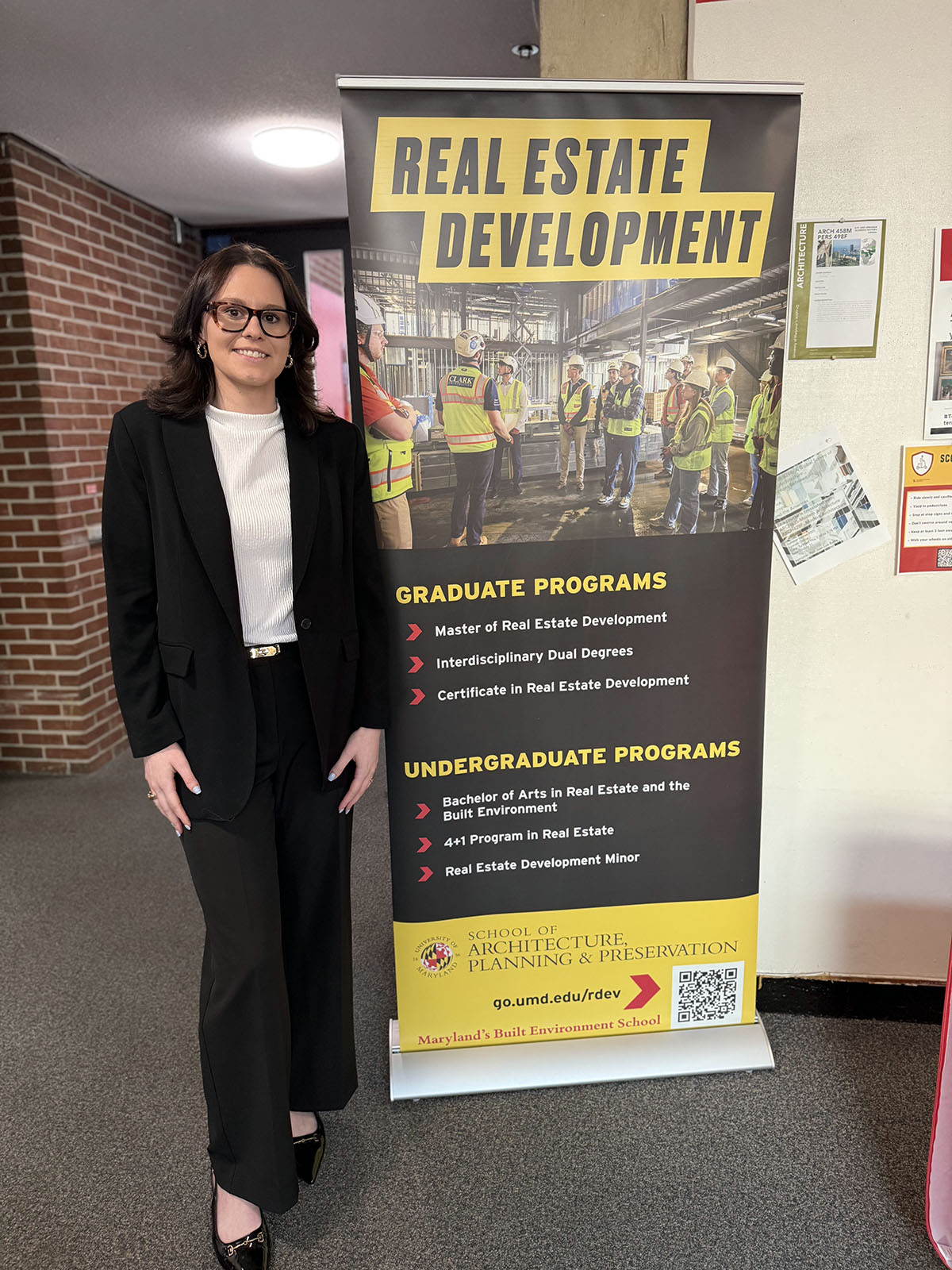 Lexi Furman standing by a Real Estate Development banner