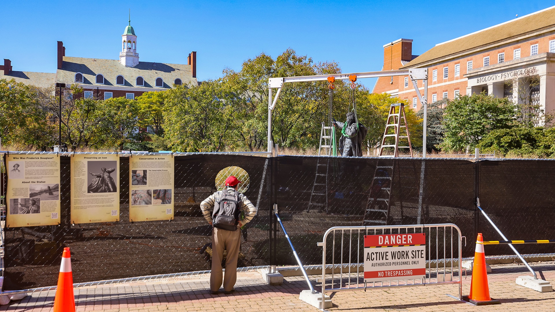 Passerby looking at the removal of the Frederick Douglas statue