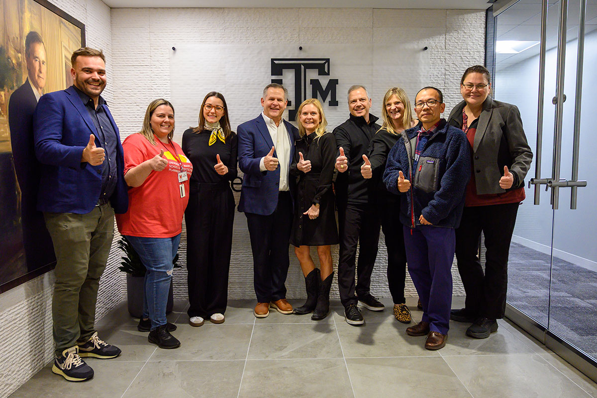 Group shot of UMD and Texas A&M faculty and staff holding the thumbs up