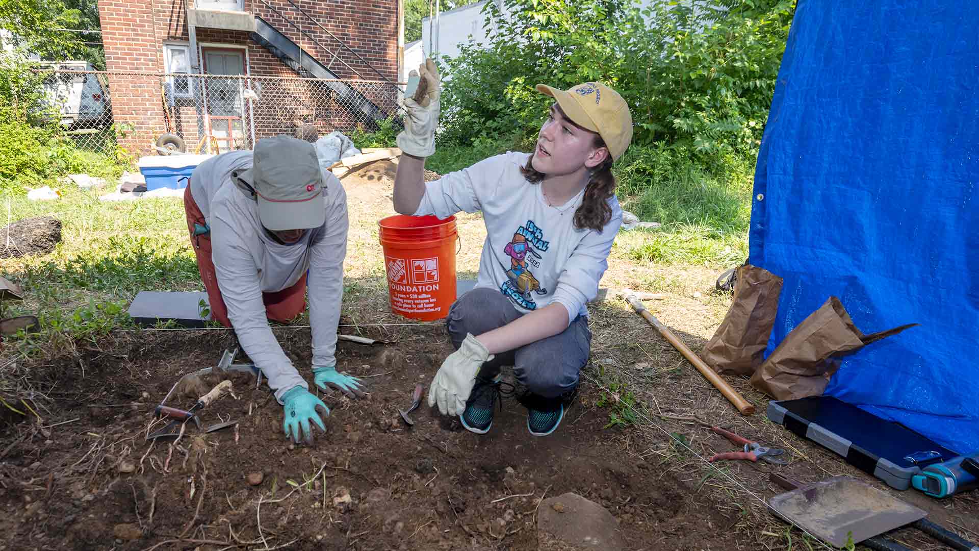 A student shows a tile found while excavating.