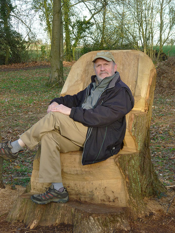 Karl Du Puy sitting in a chair made out of tree trunk