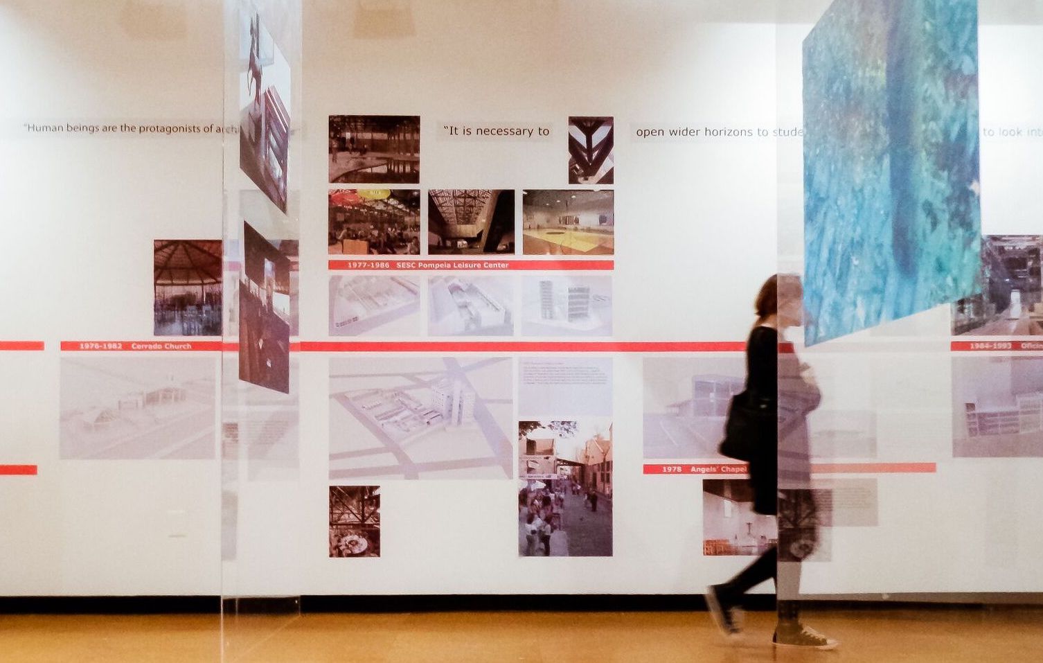 A person walking through hanging panels and by a timeline at an exhibit