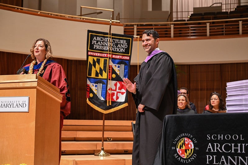 Michael Abrams waving on stage, Dean Jourdan speaking