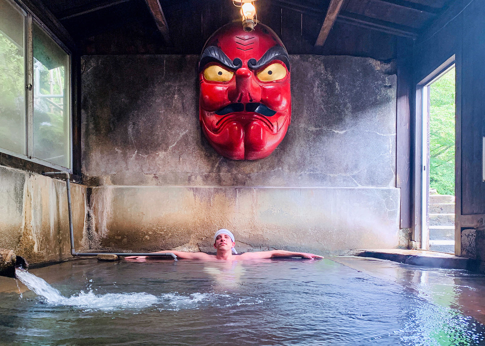 Yuval Zohar in Kita Onsen’s Tengunoyu's spa with a large red Japanese mask above his head