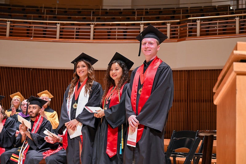Student marshals in caps and gown on stage