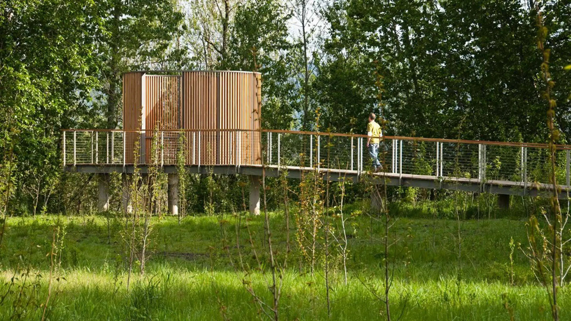 Man walking on a bridge towards a structure