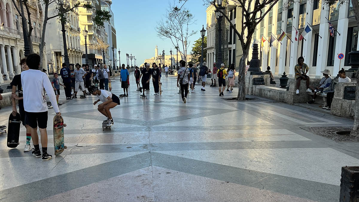 Walking street space in Havana. Children are skateboarding and people are walking / sitting. 