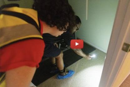 Two people looking under a wall with a flashlight for sewage backup