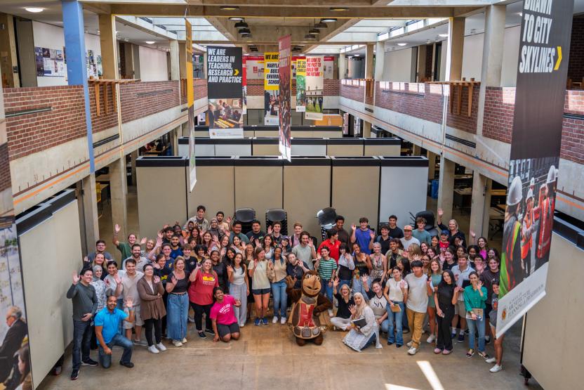 Group shot of students, faculty and staff in the Great Space with Testudo.