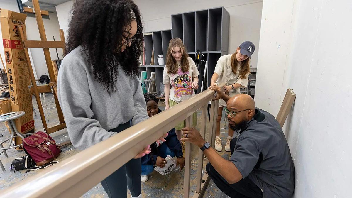 Professor Brandon Donahue helping students assemble a railing