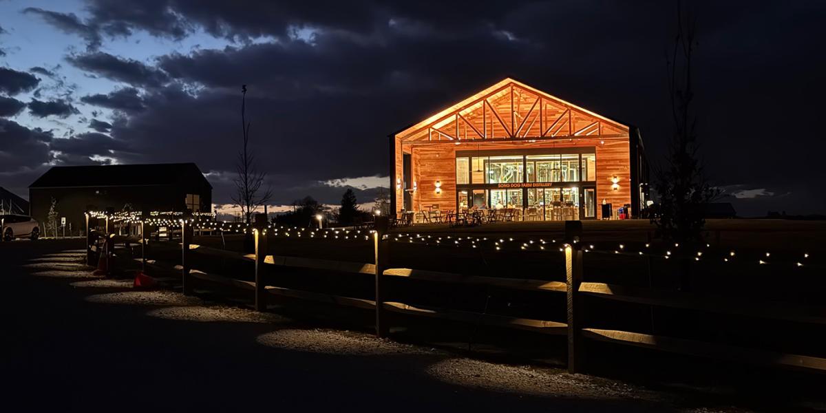 Distillery barn at sunset filled with lights. Lights on a fence are in the foreground