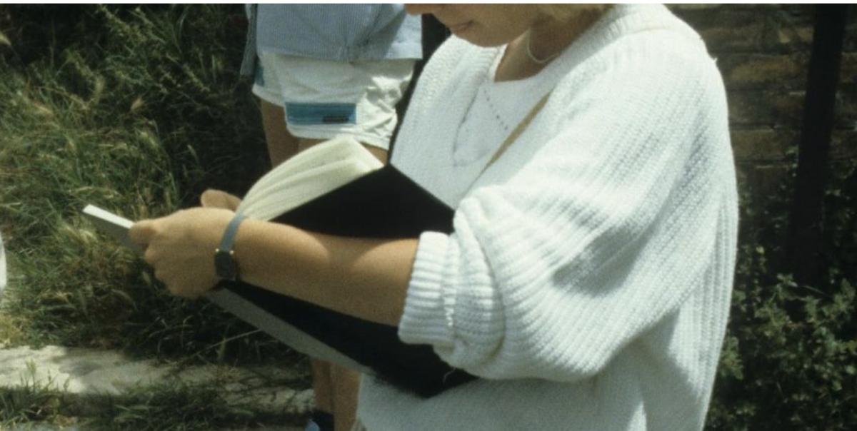 Photo of a woman, neck down, reading a book. 