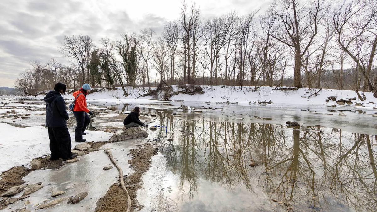 People collecting water samples from the Potomac River during a snowy winter