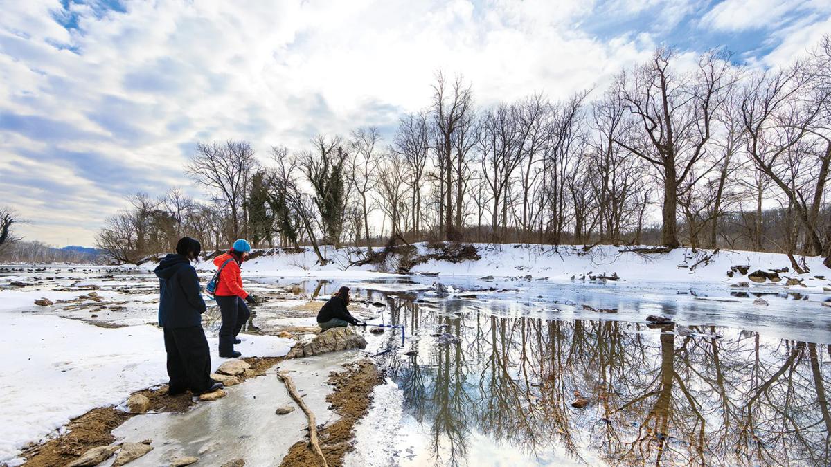 Two researchers by the Potomac rive on a cold morning, with snow on the ground