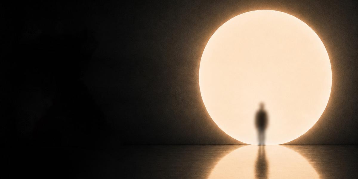 A silhouette of a person in front of a large moon or sun