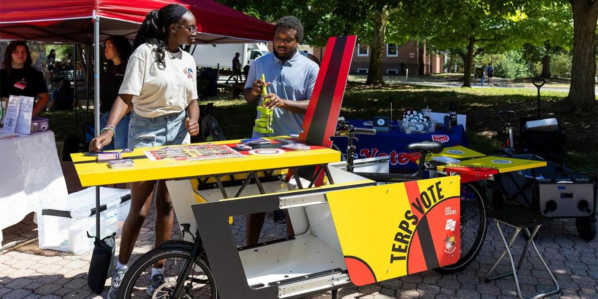 Students by the TerpsVote bicycle, learning about voting