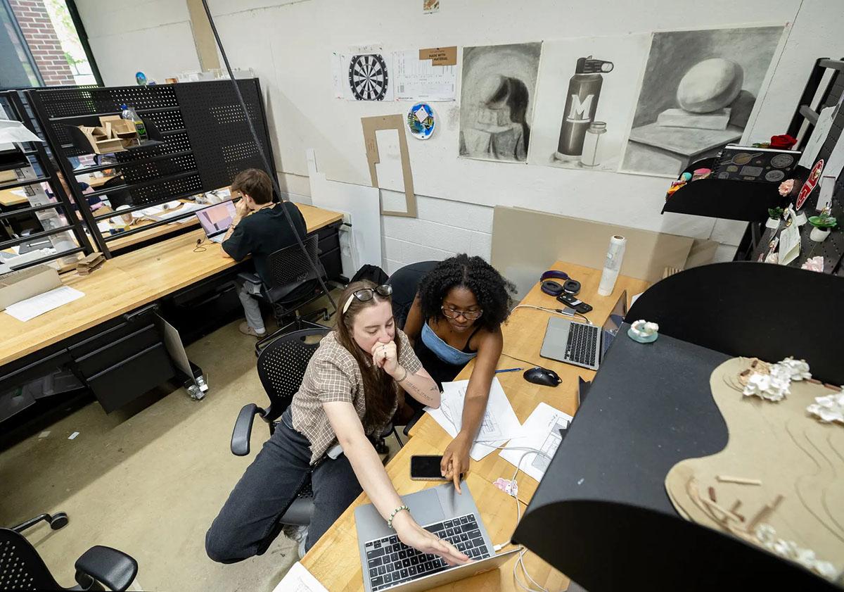 Students working at a laptop together in studio