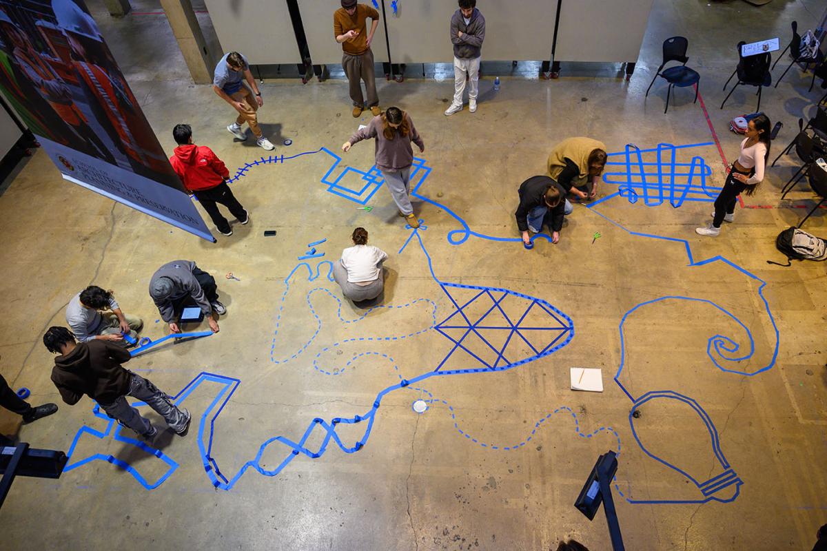 Student placing blue tape in the Great Space as part of a project