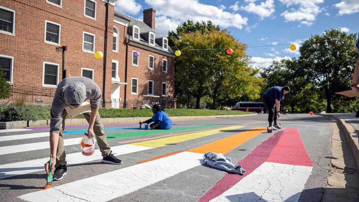 People painting crosswalk signage in various colors