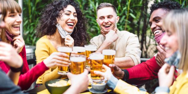 People cheering with beer, masks pulled down their faces