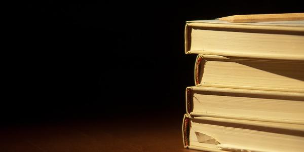 Stacked books on a wooden table and a dark background