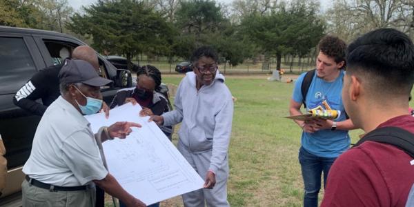 Andrea Roberts holding cemetery map with Doc Williams and undergraduate students.