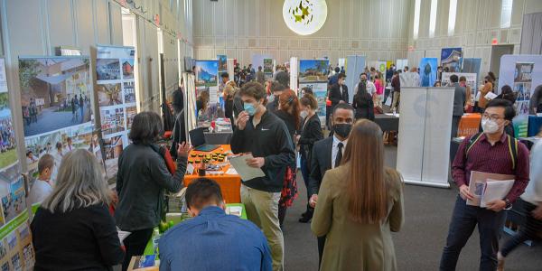 People wearing masks are chatting at booths during a career fair.