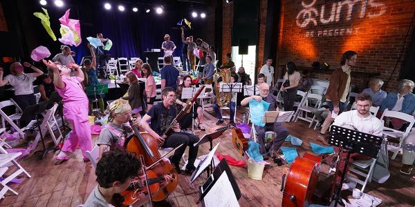 People playing instruments and throwing colorful paper in the air.