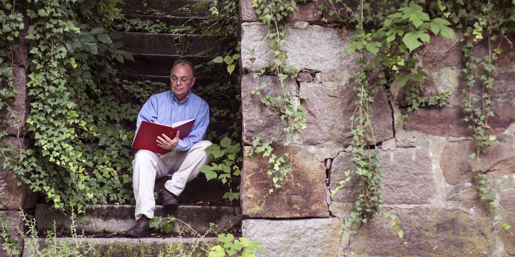 Willie Graham reading a book on a stone staircase.
