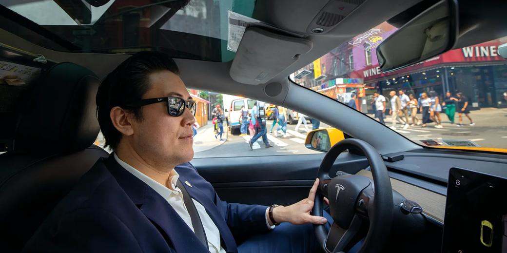 David Do wearing sunglasses in his Tesla taxi.