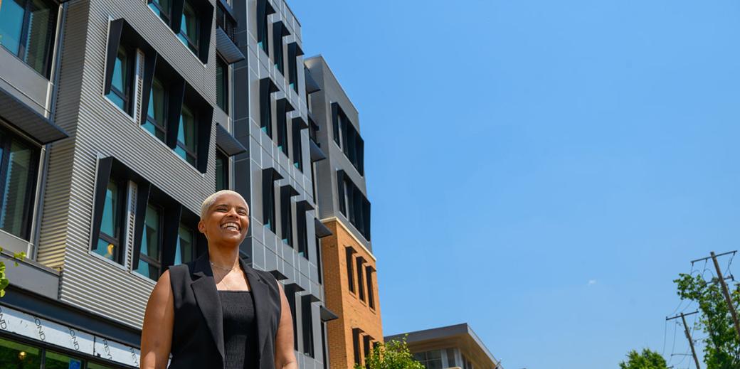 Maia Shanklin-Roberts in front of housing with a bright blue sky in the background