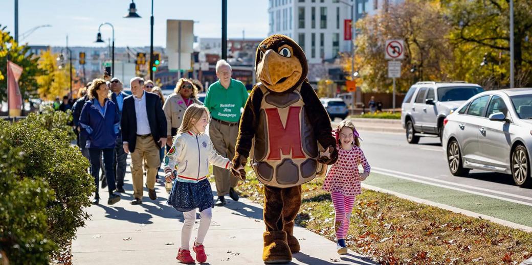 Testudo mascot walking with children on a sidewalk. 