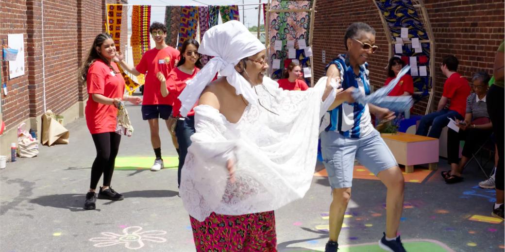 Woman wearing white in the foreground leading people to a dance
