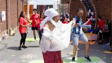 Woman wearing white in the foreground leading people to a dance