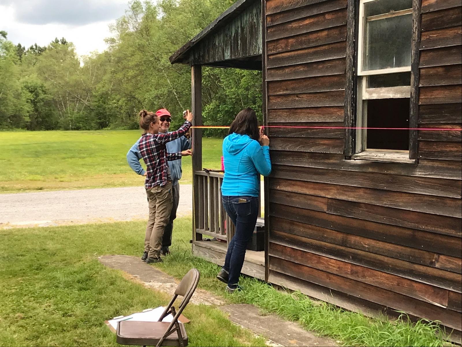 Historic preservation students measuring a wooden house.