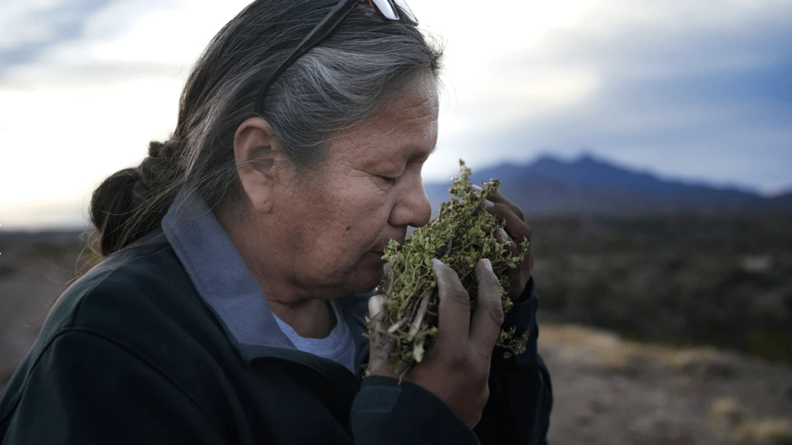 Native American woman smelling herbs. 
