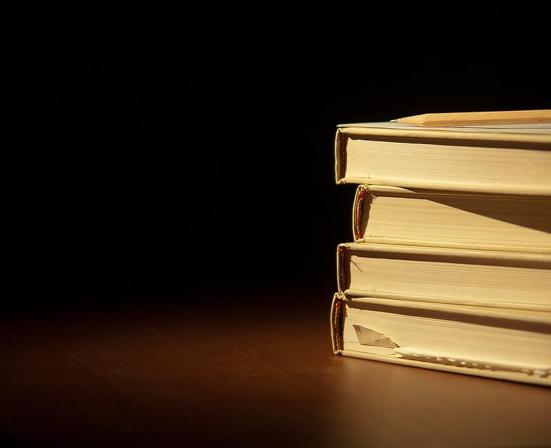 Stacked books on a wooden table and a dark background