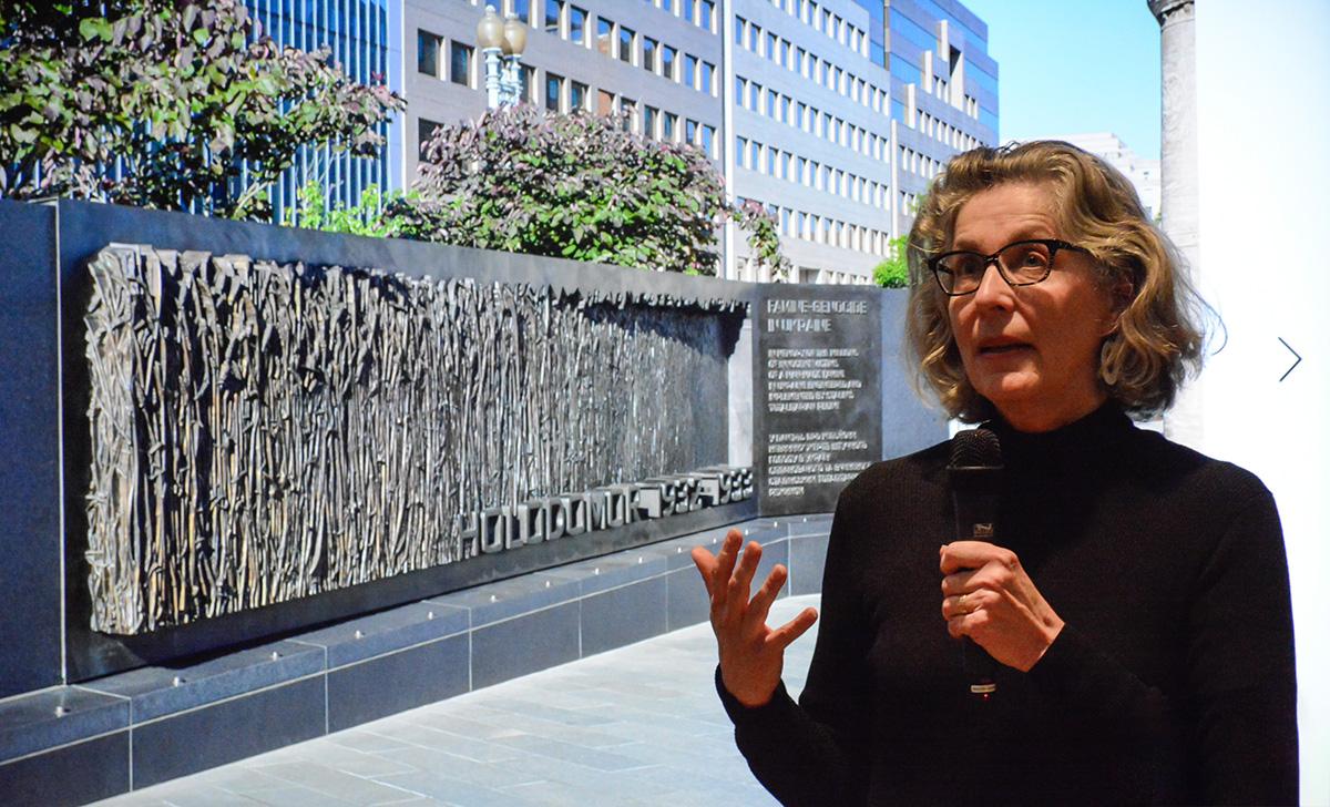 Larysa Kurylas presenting the Holodomor Memorial, which is pictured in the screen behind her.