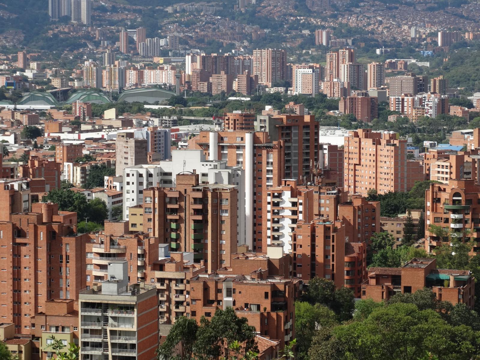 Tall Columbian buildings surrounded by greenery. 