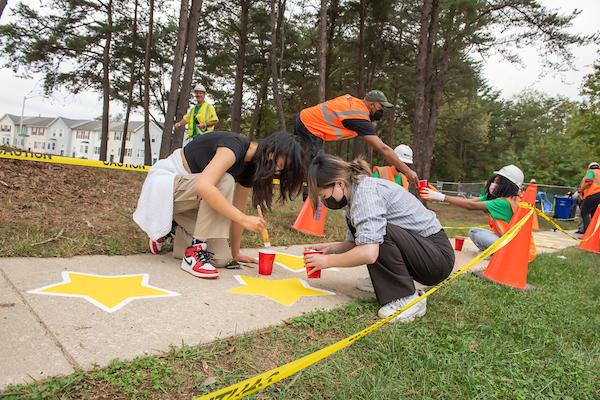 Students painting yellow stars on sidewalk as part of a Creative Placemaking project
