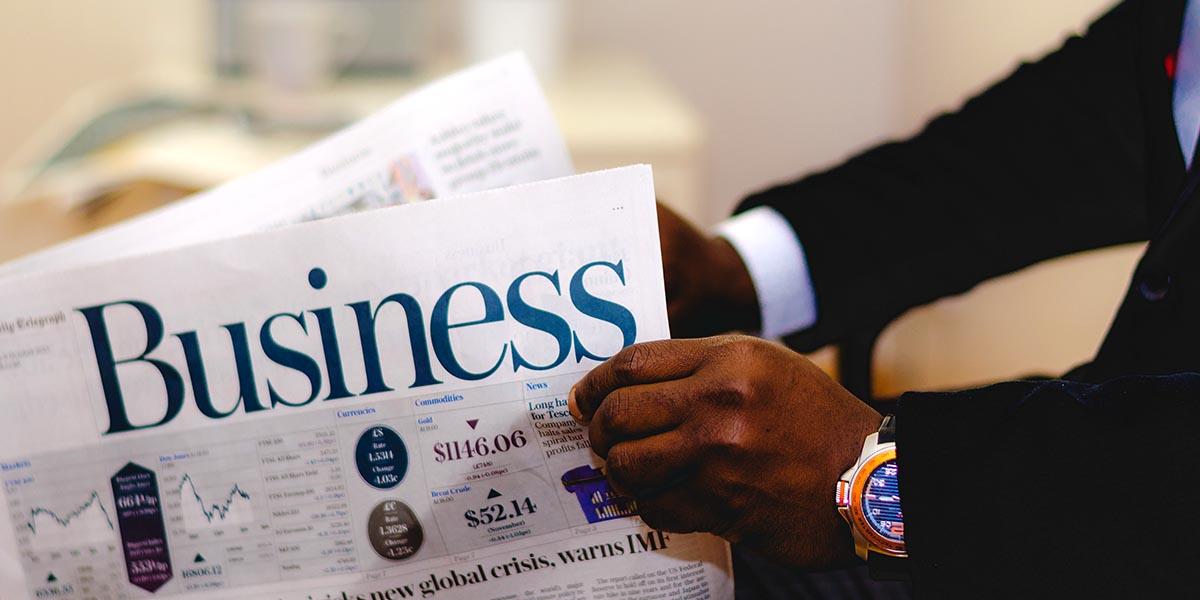 Man with blue watch holding a Business newspaper