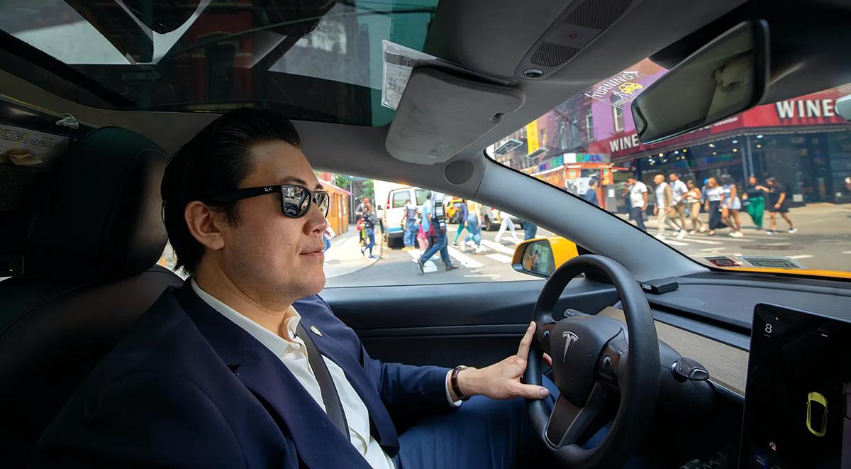 David Do wearing sunglasses in his Tesla taxi.