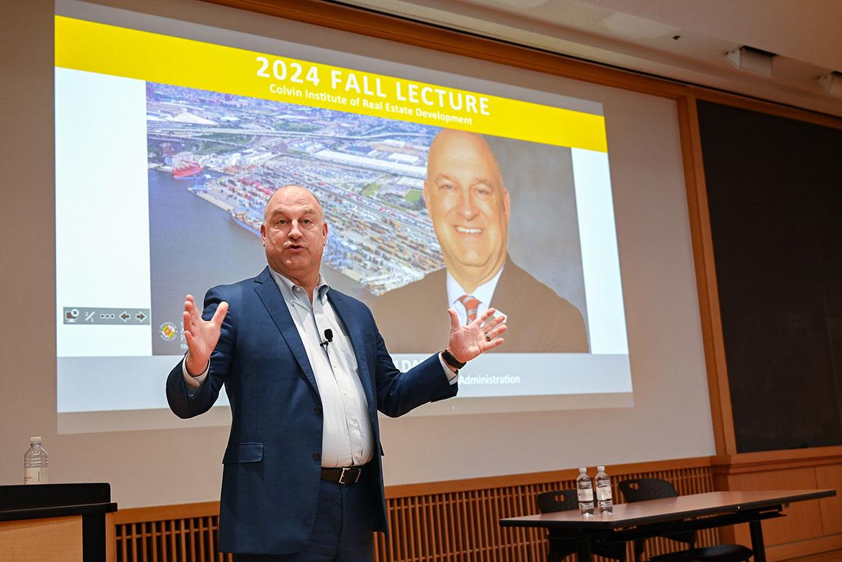 Jonathan Daniels presenting in front of a Powerpoint slide with the Baltimore Harbo