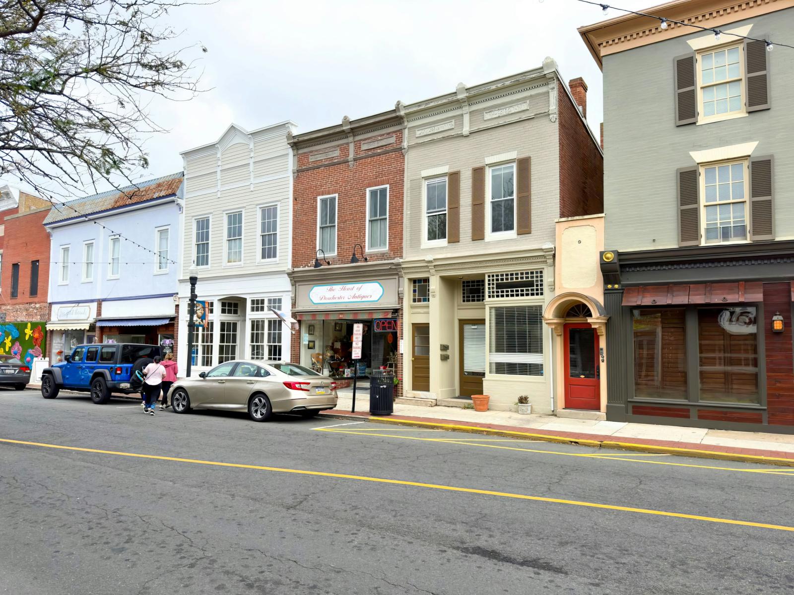 Housing and retail on a main street with cars in front