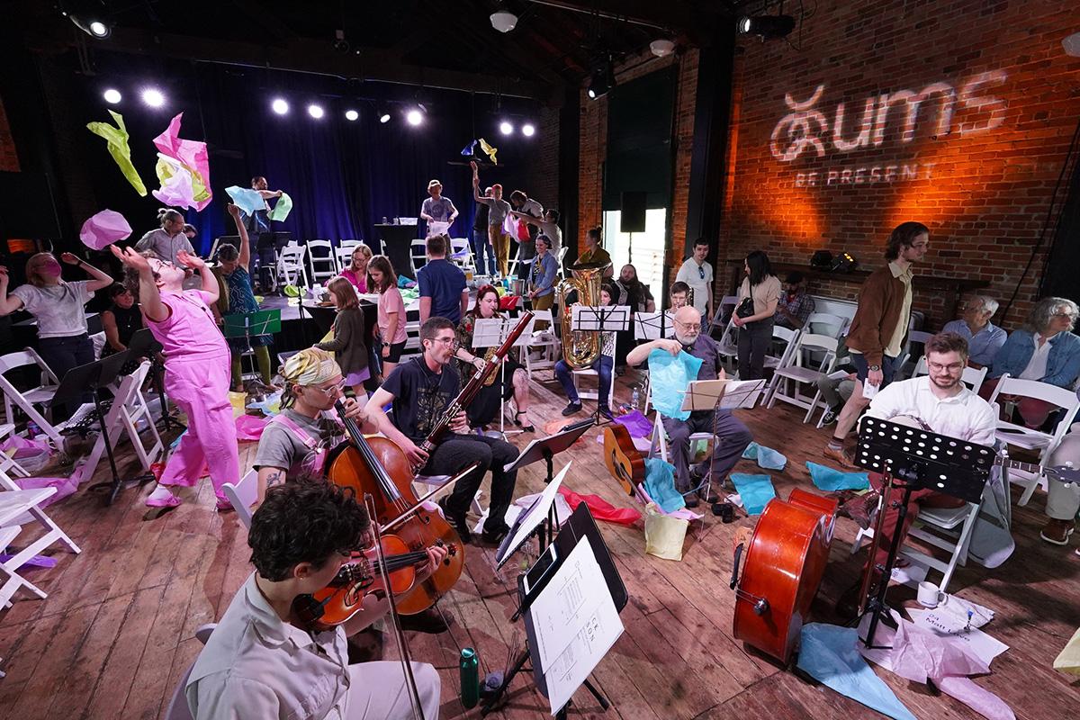 People playing instruments and throwing colorful paper in the air.