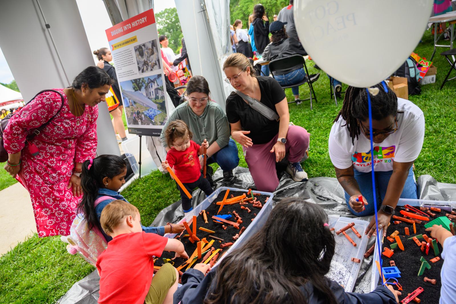 Children digging into bins to unravel pieces of toy buildings at Maryland Day.
