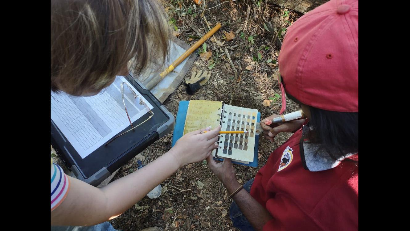 Students looking at a notebook and pointing to it