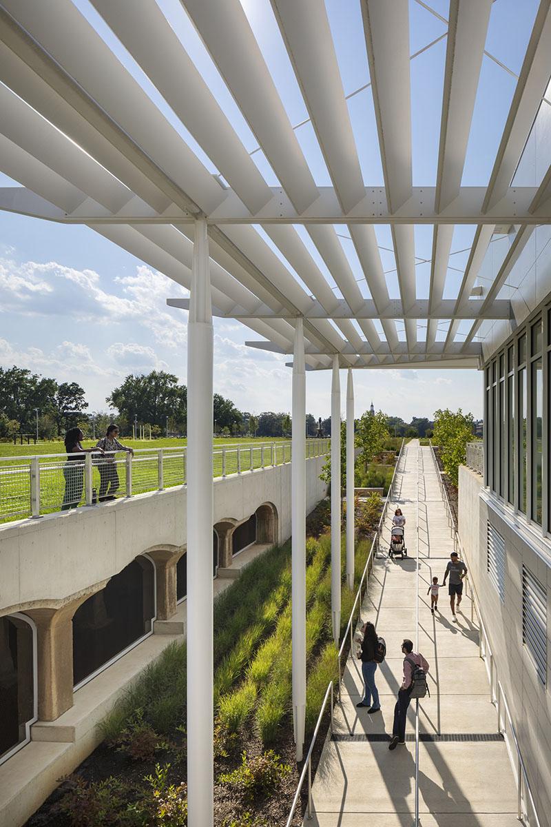 Exterior walkway with a white overhead structure at the Reservoir District Recreation Center.