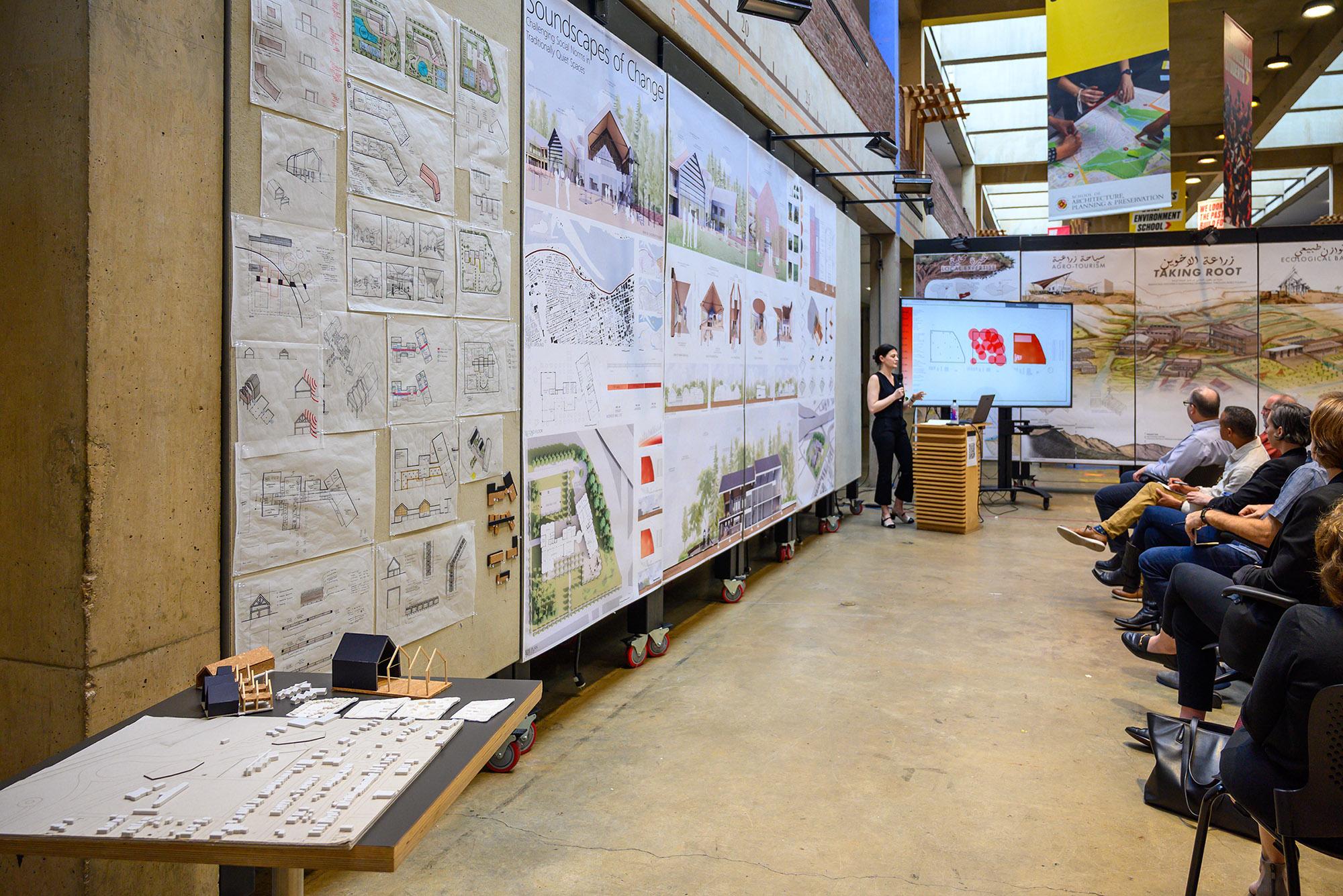 Presenter at the front of a classroom decked with posters and models